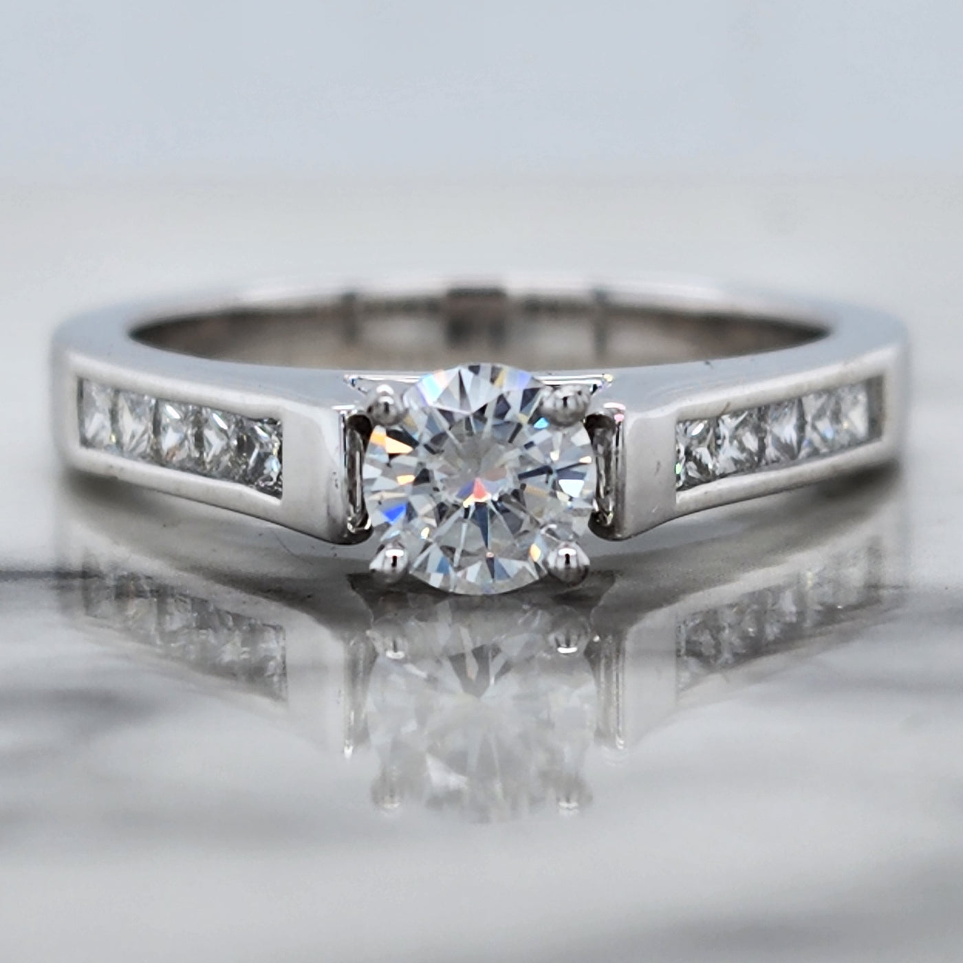 White Gold Engagement Ring With Round Diamond and Channel Set Princess Cut Accents